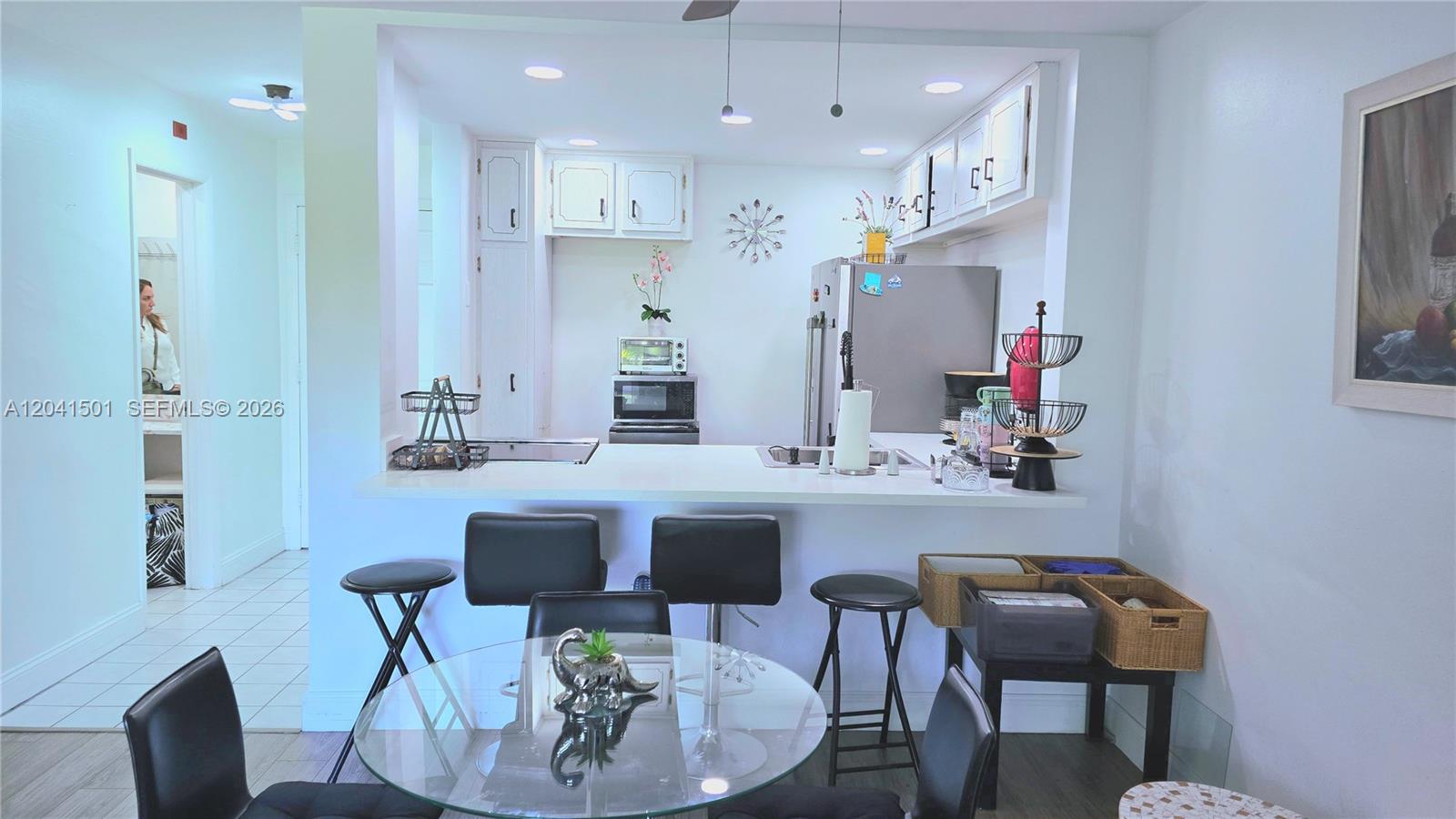 A kitchen features white cabinets, stainless steel appliances, and a breakfast bar with stools — 9611 SW 77th Ave # 305A, Miami FL 33156, MIAMI, FL
