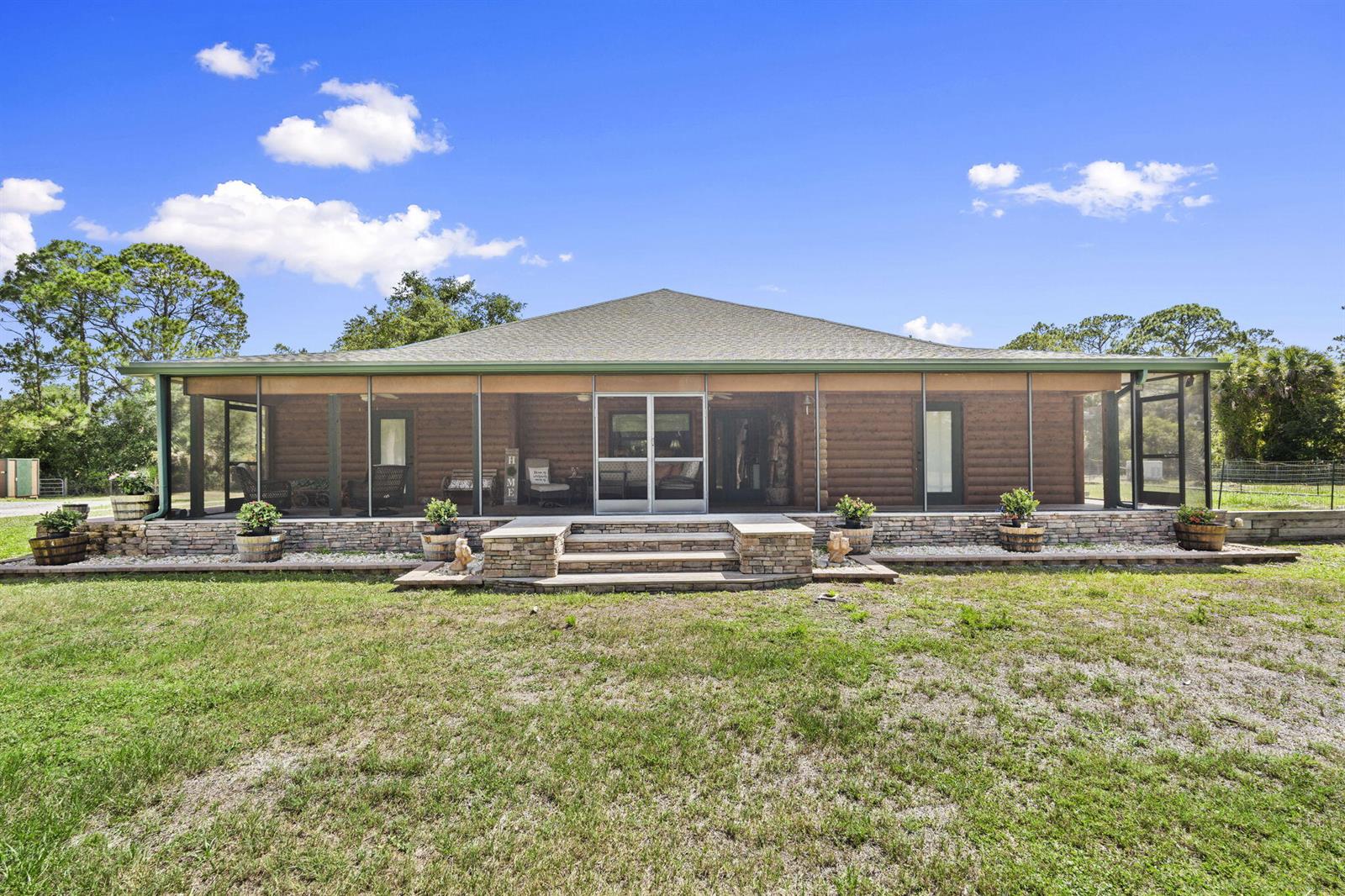 A single-story log cabin features a large screened-in porch and a stone-faced foundation — 32801 N Us Highway 441 N # 52, Okeechobee FL 34972, OKEECHOBEE, FL