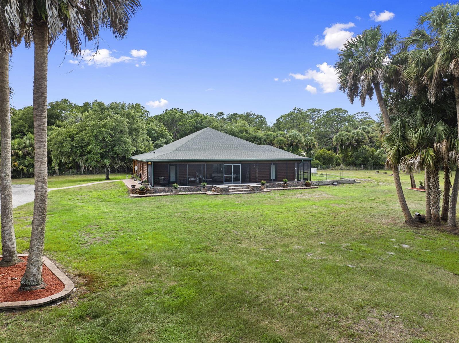 A single-story log cabin with a screened-in porch sits on a large, grassy lot — 32801 N Us Highway 441 N # 52, Okeechobee FL 34972, OKEECHOBEE, FL