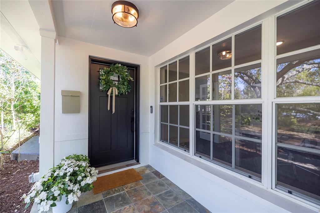A covered front porch features a dark door with a wreath and large grid windows — 1433 PARK STREET N, ST PETERSBURG, FL