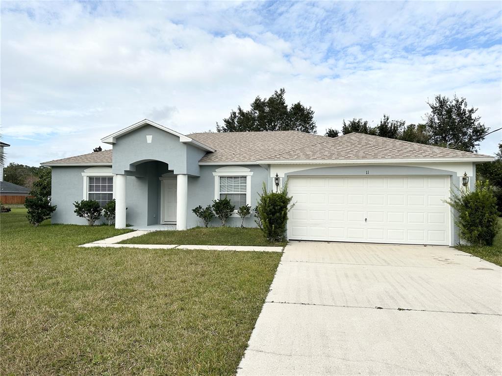 A single-story house with a light blue exterior, a two-car garage, and a covered entryway — 11 PRAVER LANE, PALM COAST, FL