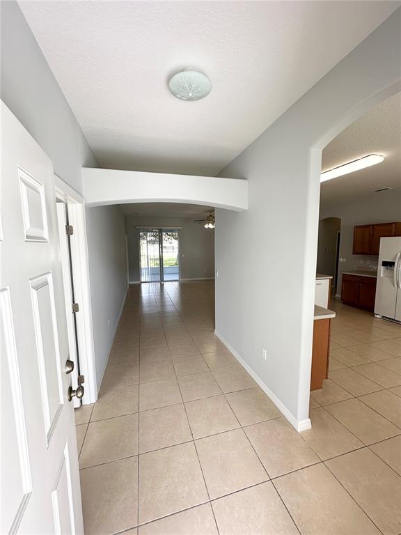 An entryway with tile flooring leads to a living area with sliding glass doors — 11 PRAVER LANE, PALM COAST, FL