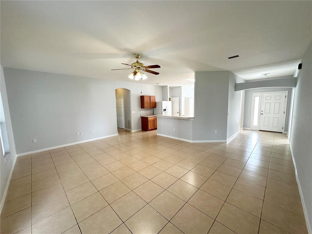An open-concept living area features light gray walls, tiled floors, and a kitchen with cabinets — 11 PRAVER LANE, PALM COAST, FL