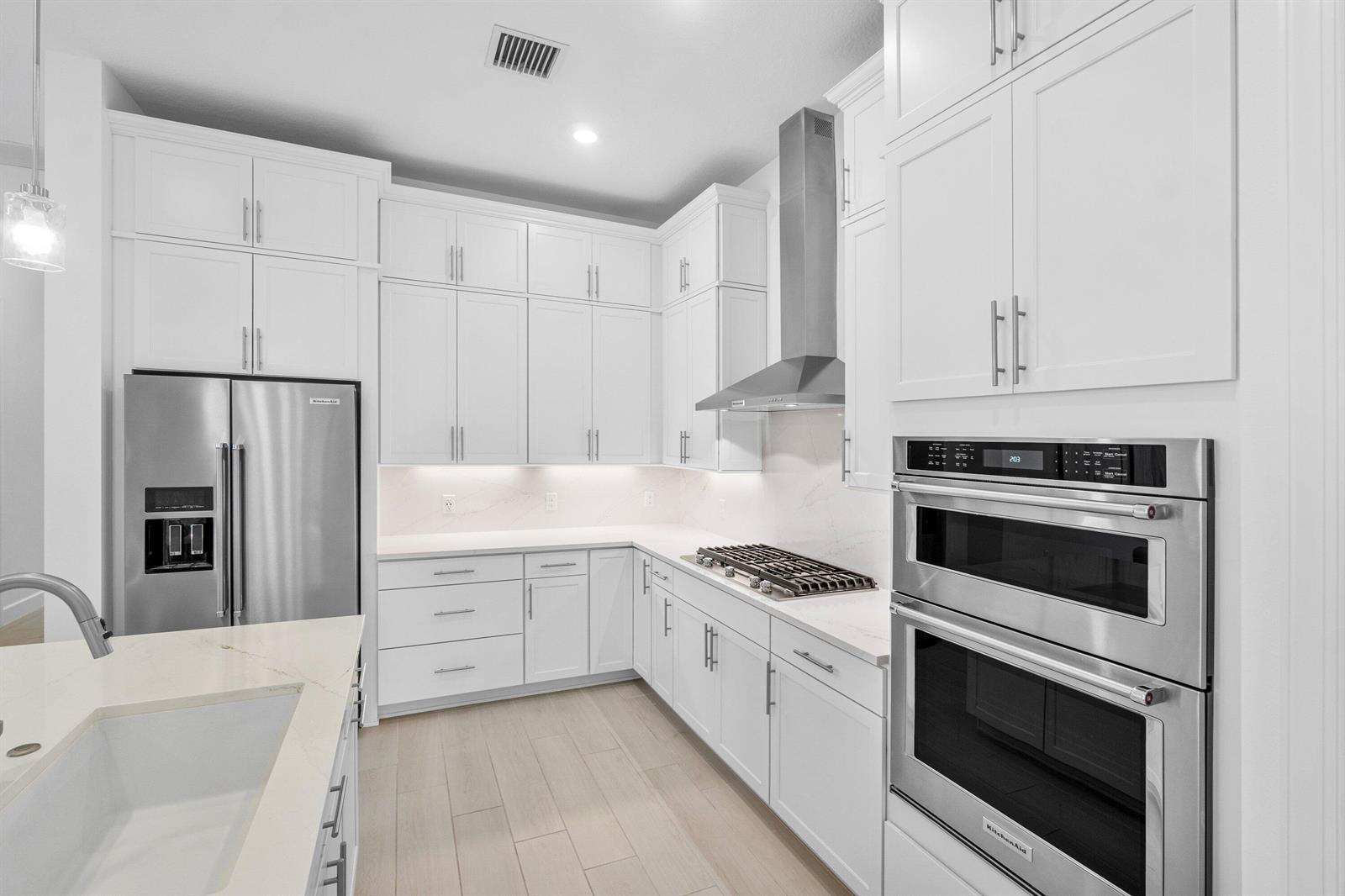 An open-concept living room and kitchen with light wood floors and a large sectional sofa — 9303 Cape Honey Bee Lane, Lake Worth FL 33467, LAKE WORTH, FL