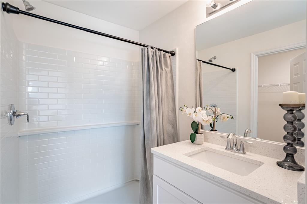 A bathroom features a white subway tile shower, a vanity with a quartz countertop, and mirror — 2348 FINTONROD STREET, PORT CHARLOTTE, FL