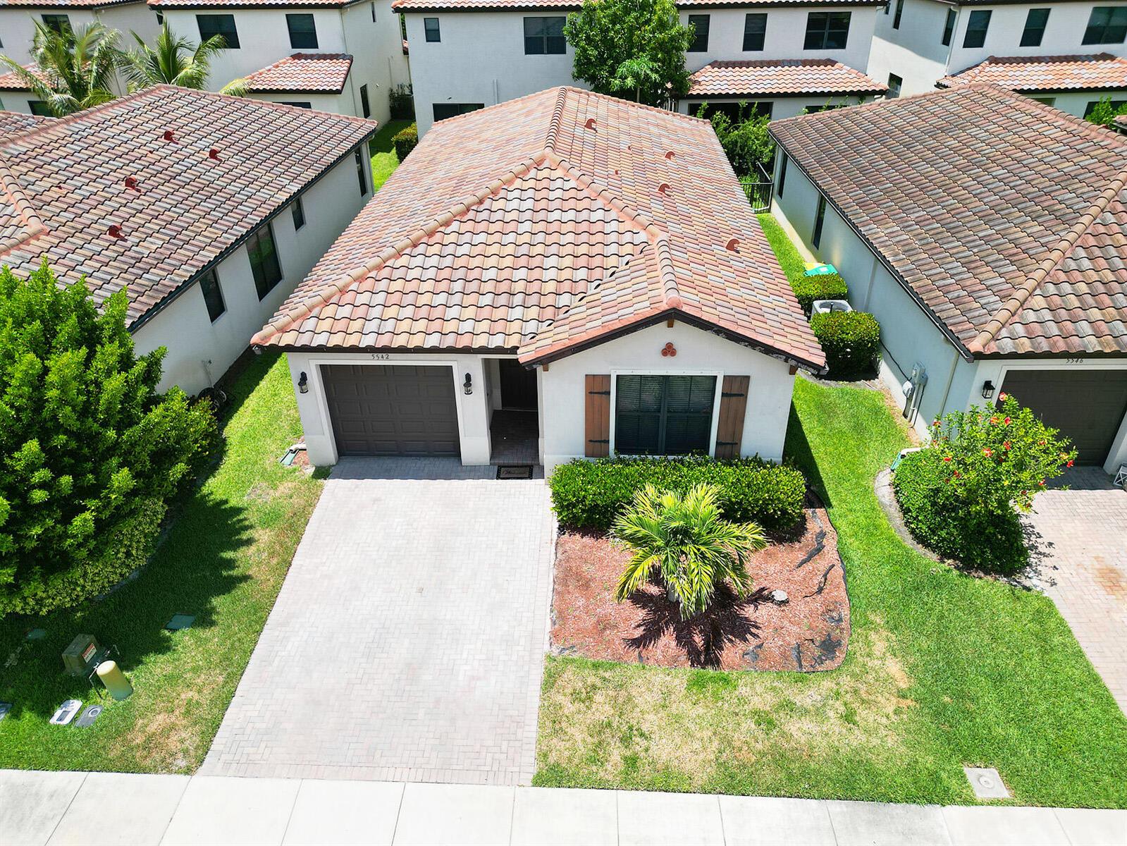 An aerial view shows a single-story house with a tiled roof, driveway, and landscaped yard — 5542 Useppa Drive, Ave Maria FL 34142, AVE MARIA, FL