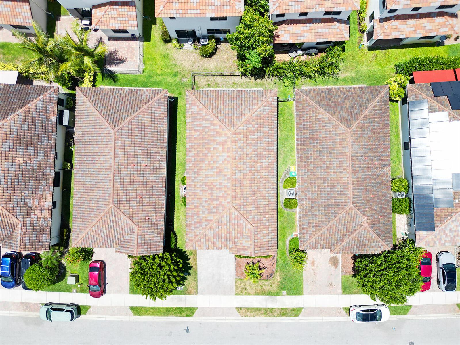 An aerial view shows three residential houses with tiled roofs and driveways along a street — 5542 Useppa Drive, Ave Maria FL 34142, AVE MARIA, FL