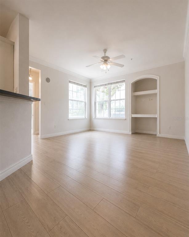 An empty room with light wood-look flooring, a ceiling fan, and a built-in arched alcove — 3213 GREENWICH VILLAGE BOULEVARD UNIT 102, ORLANDO, FL