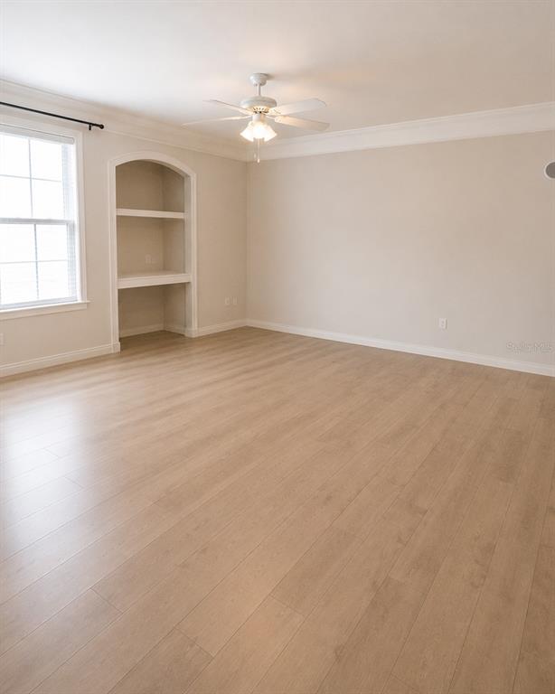 An empty room features light wood-look flooring, a ceiling fan, and a built-in arched alcove — 3213 GREENWICH VILLAGE BOULEVARD UNIT 102, ORLANDO, FL