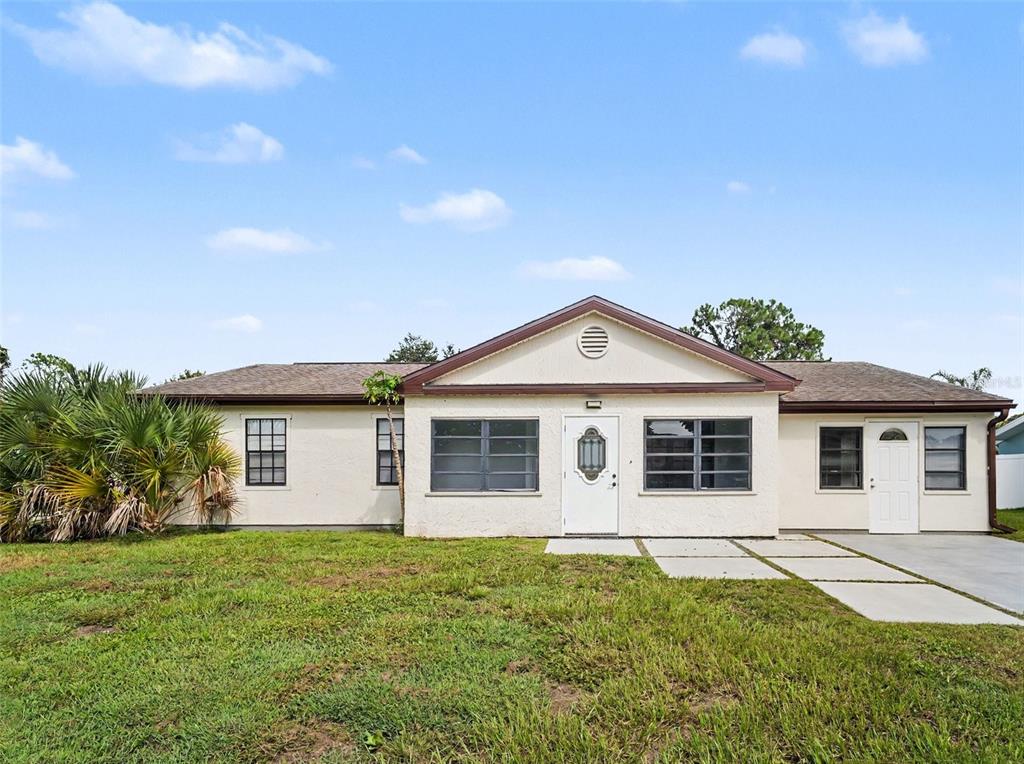 A single-story house with a white stucco exterior, a gabled roof, and a front lawn — 4060 AVANTI CIRCLE, NORTH PORT, FL