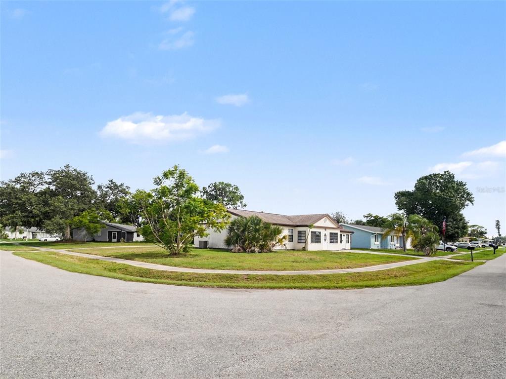A corner lot features a single-story house with a light-colored exterior and a grassy lawn — 4060 AVANTI CIRCLE, NORTH PORT, FL