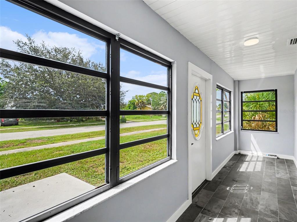 A sunroom features gray walls, dark tile flooring, large windows, and a white door — 4060 AVANTI CIRCLE, NORTH PORT, FL