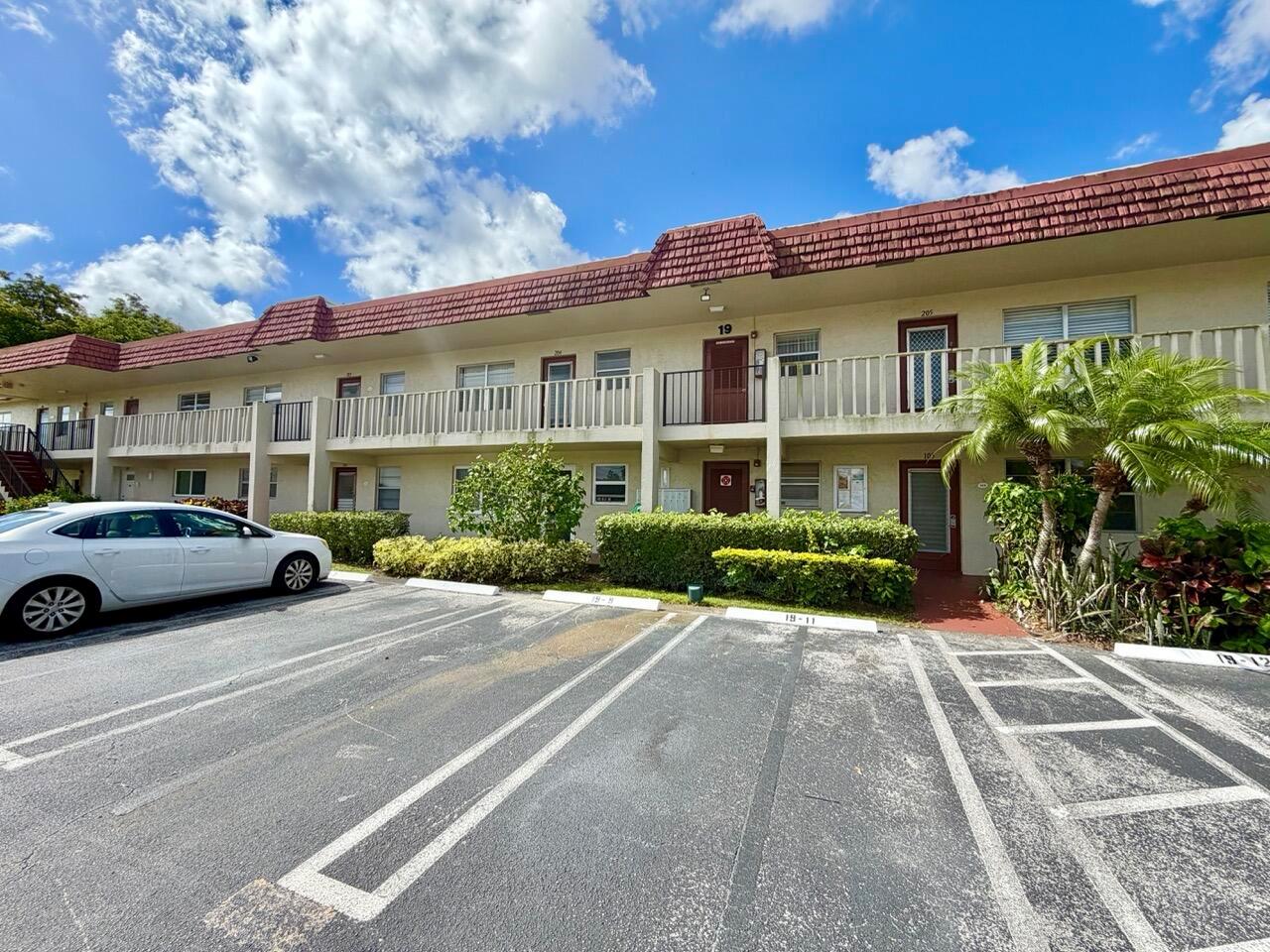 A two-story apartment building with a red tile roof and a parking lot in front — 19 Abbey Lane # 204, Delray Beach FL 33446, DELRAY BEACH, FL