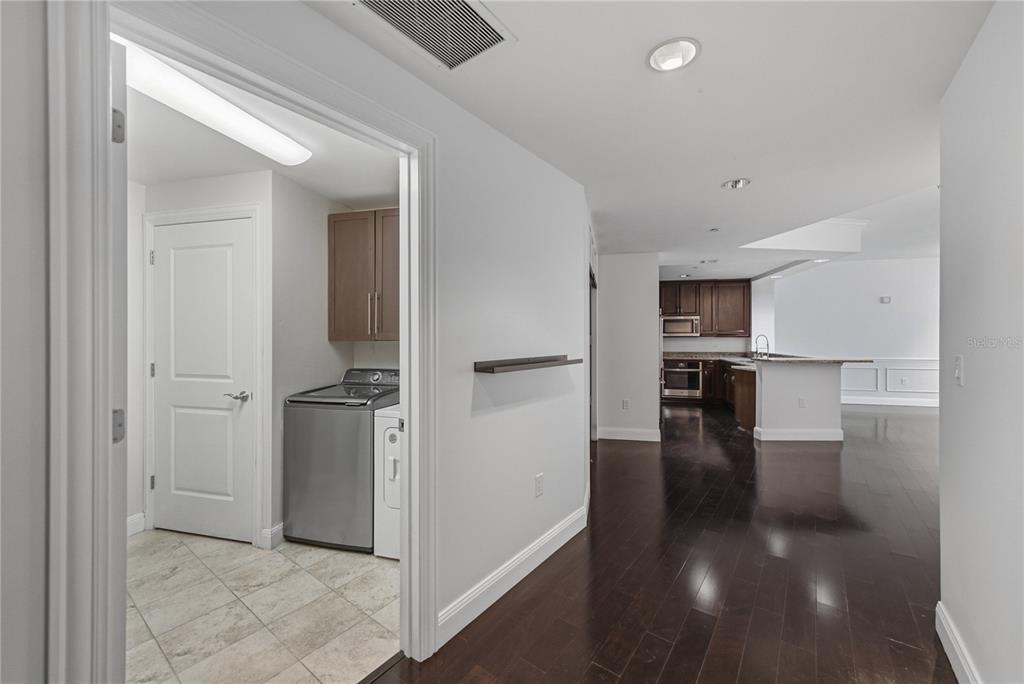 A hallway features two doors, a patterned carpet, and a console table with artwork above — 450 KNIGHTS RUN AVENUE UNIT 1103, TAMPA, FL