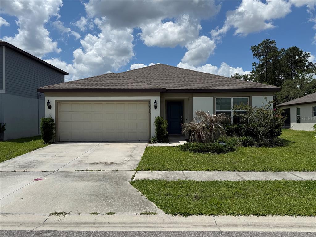 A single-story house with a beige garage, white stucco walls, and a dark shingled roof — 30596 THUNDERBIRD DRIVE, WESLEY CHAPEL, FL