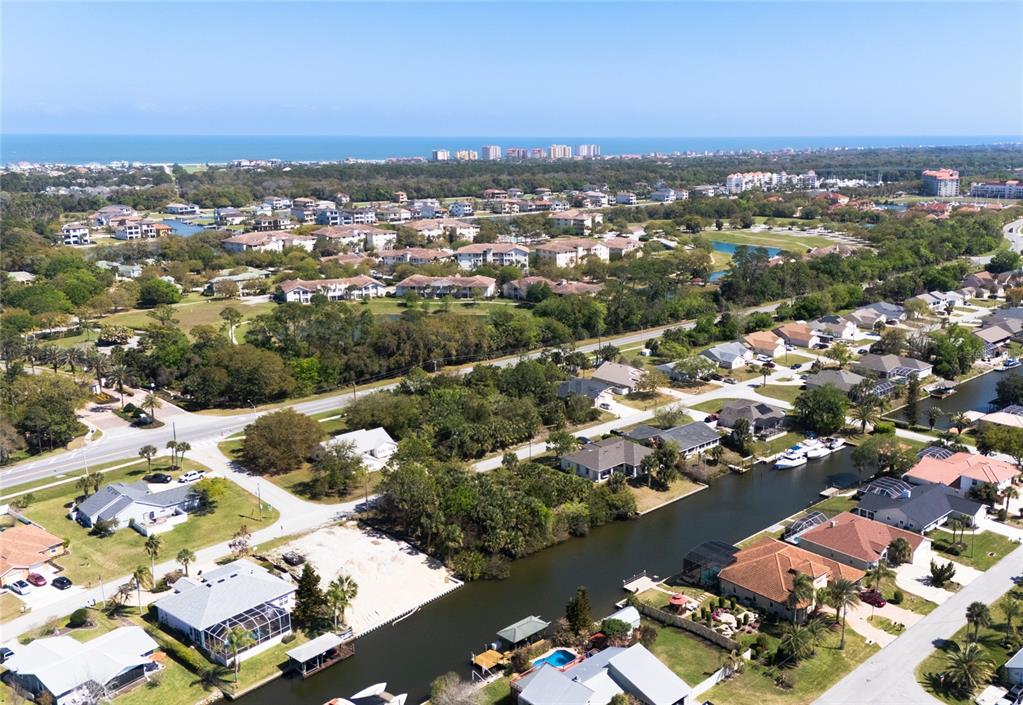 An aerial view shows residential homes along a canal with the ocean in the distance — 60 CORAL REEF COURT N, PALM COAST, FL