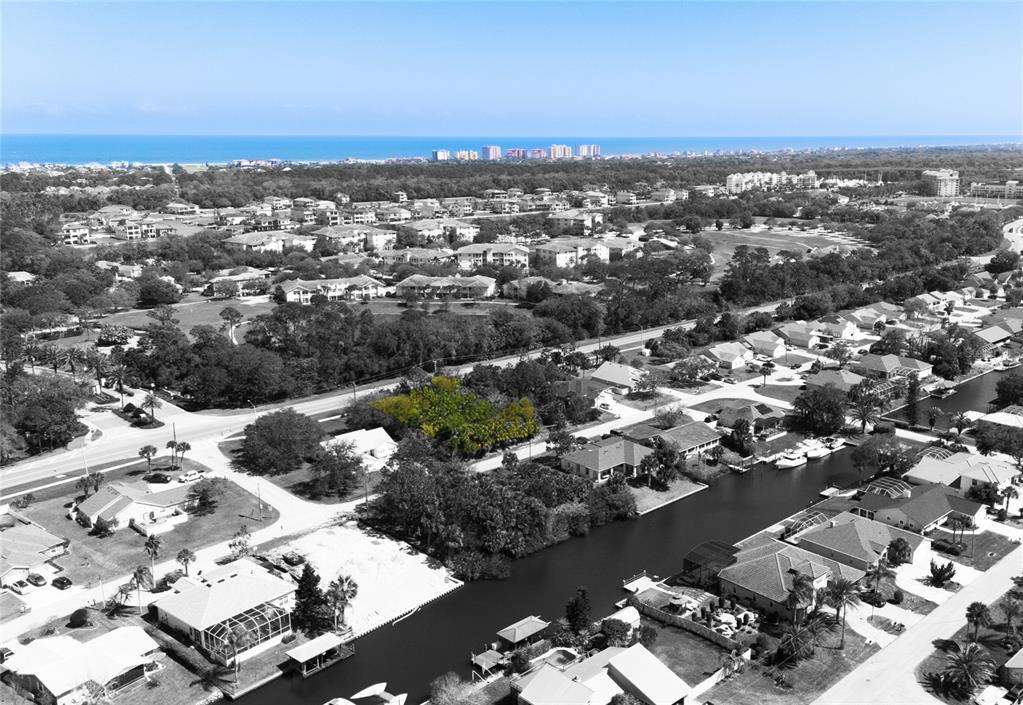 An aerial view shows a vacant, tree-covered lot situated within a residential waterfront neighborhood — 60 CORAL REEF COURT N, PALM COAST, FL