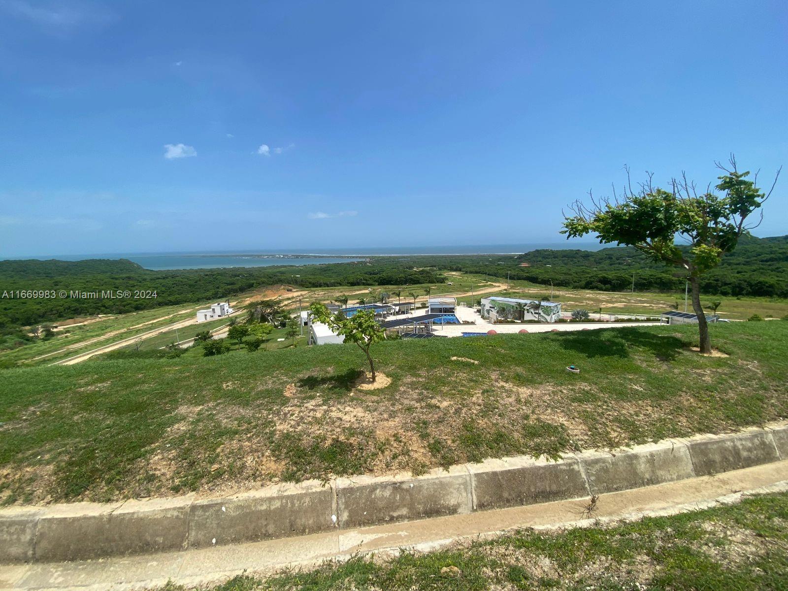 An elevated view of a grassy hillside overlooking a coastal landscape with modern buildings — 90 90A, Tubará, Atlántico, Colombia, FL, FL