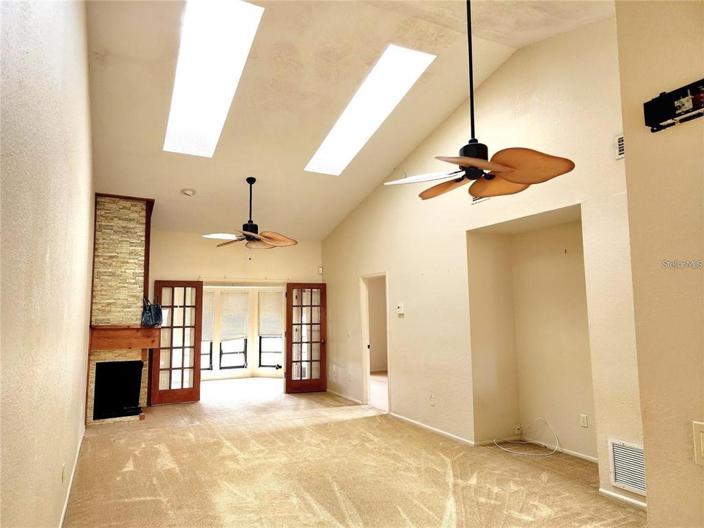 A living room with a vaulted ceiling, skylights, ceiling fans, a stone fireplace, and carpet — 4356 MIDDLEBROOK ROAD UNIT 3, ORLANDO, FL