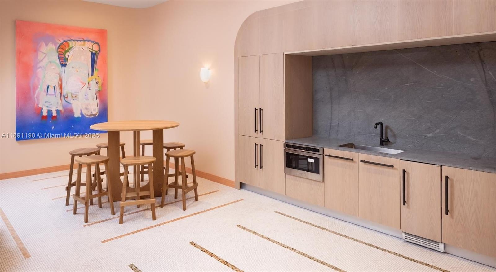 A kitchenette with light wood cabinetry and a small dining area with stools — 11200 Biscayne Blvd # B2, Miami FL 33181, MIAMI, FL