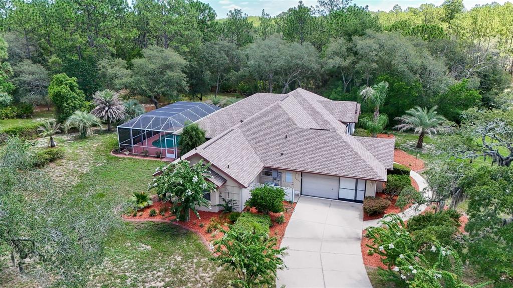 An aerial view shows a single-story house with a screened pool and a paved driveway — 4921 N CHEYENNE DRIVE, BEVERLY HILLS, FL