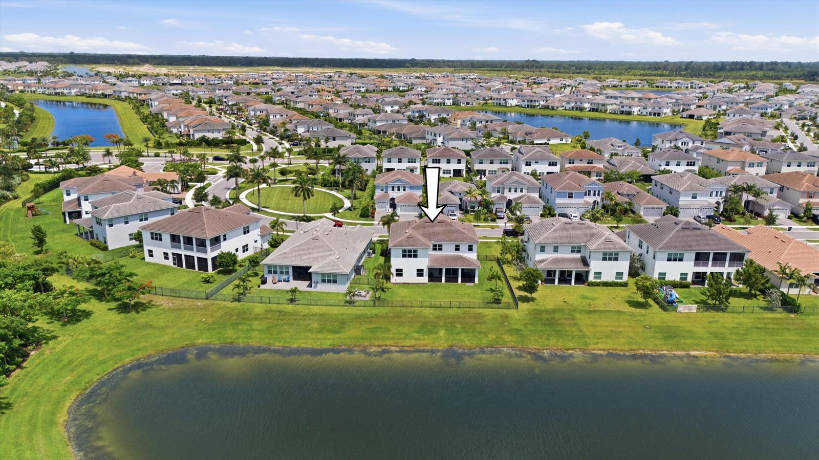 An aerial view shows a two-story house with a screened lanai facing a lake — 5669 Liberty Lane, Westlake FL 33470, WESTLAKE, FL