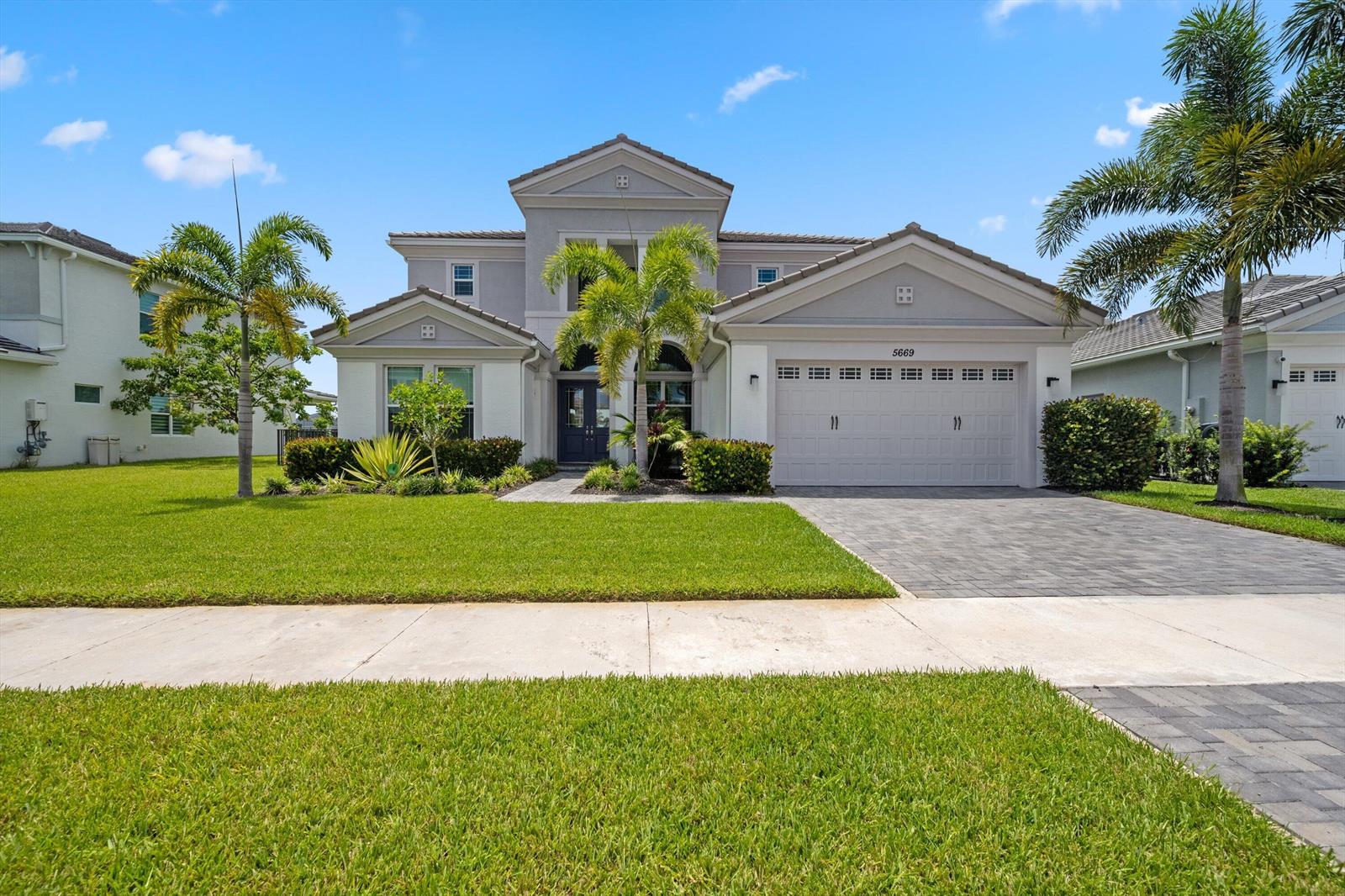 A two-story suburban house features a paved driveway, a three-car garage, and palm trees — 5669 Liberty Lane, Westlake FL 33470, WESTLAKE, FL