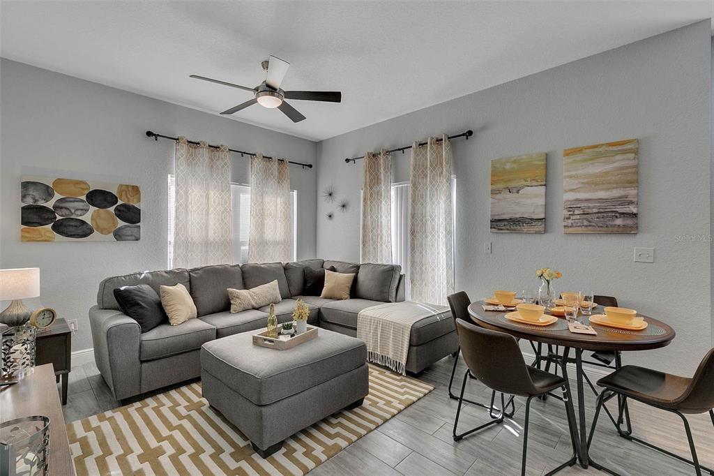 A living room with a gray sectional sofa, ottoman, and a small dining area — 4561 YELLOWGOLD ROAD E UNIT 102, KISSIMMEE, FL