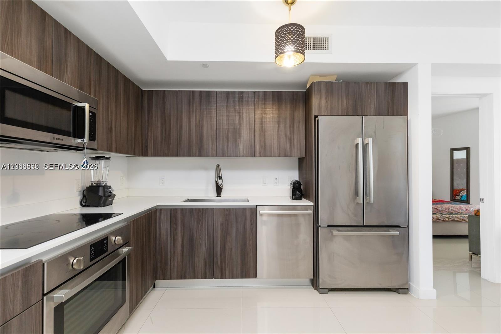 A modern open-concept living and dining area features tile flooring, stainless steel appliances, and pendant lighting — 488 NE 18th St # 2802, Miami FL 33132, MIAMI, FL