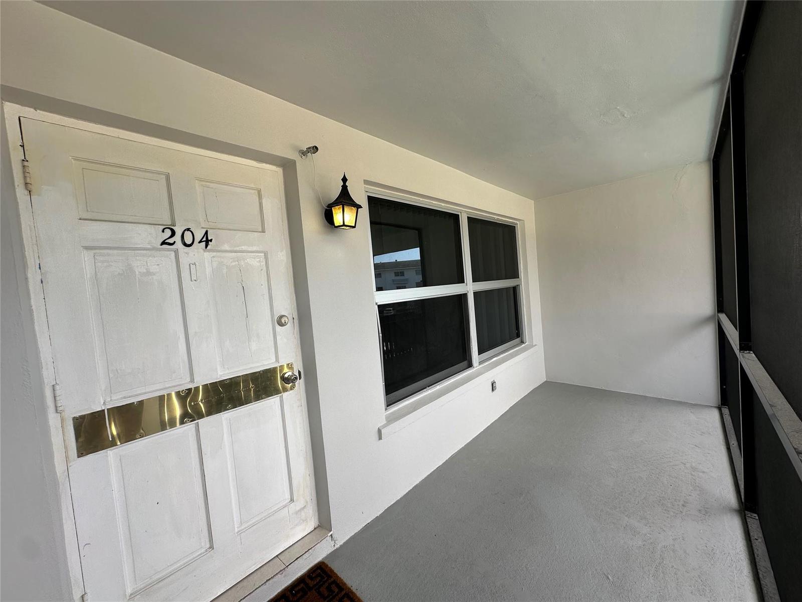 A white door marked 204 and a window open onto a covered gray porch — 651 Pine Drive, Pompano Beach FL 33060, POMPANO BEACH, FL