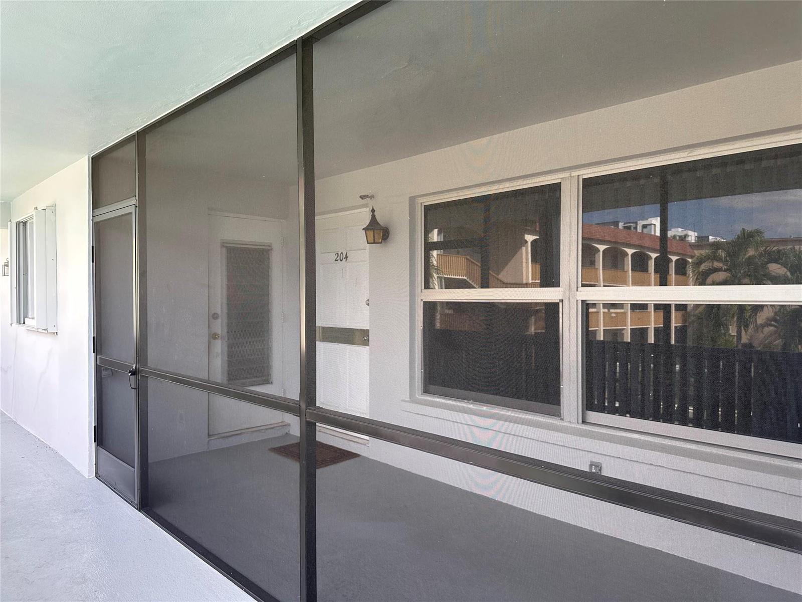 A screened-in porch features a white entry door labeled 204 and large windows — 651 Pine Drive, Pompano Beach FL 33060, POMPANO BEACH, FL