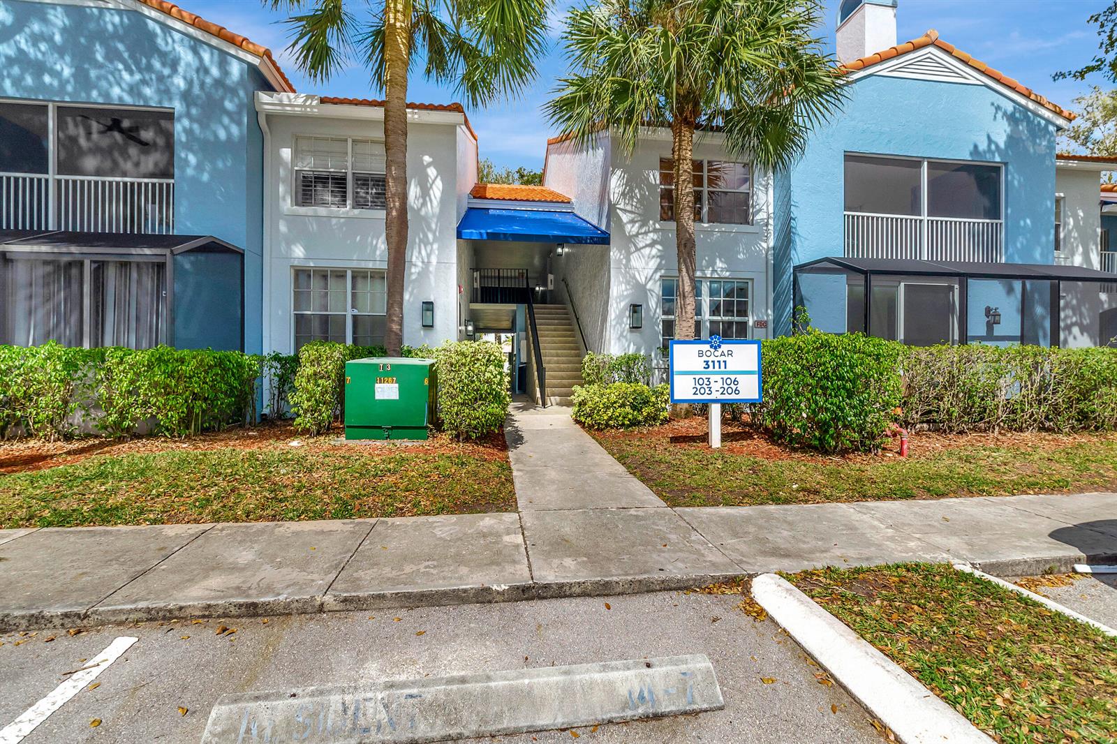 A two-story apartment building with a blue awning, stairs, and a parking lot in front — 3111 Clint Moore Road # 203, Boca Raton FL 33496, BOCA RATON, FL