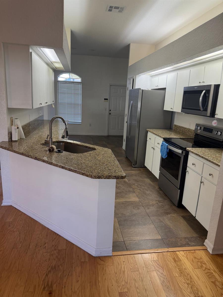 A kitchen features white cabinets, granite countertops, stainless steel appliances, and tile flooring — 123 Ruby Lake Drive, Winter Haven FL 33884, WINTER HAVEN, FL