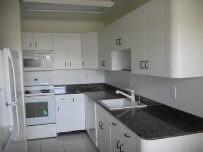 A kitchen features white cabinets, dark granite countertops, a white stove, and a white sink — 1561 NW 20th Avenue # 101, Delray Beach FL 33445, DELRAY BEACH, FL