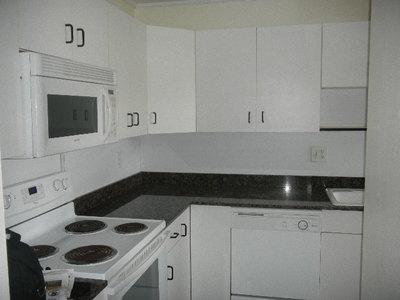 A kitchen with white cabinets, dark countertops, a white electric stove, and a microwave — 1561 NW 20th Avenue # 101, Delray Beach FL 33445, DELRAY BEACH, FL