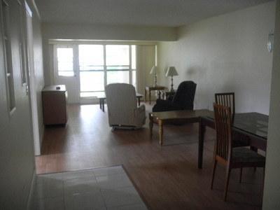 An open-concept living and dining area features wood-look flooring and a sliding glass balcony door — 1561 NW 20th Avenue # 101, Delray Beach FL 33445, DELRAY BEACH, FL