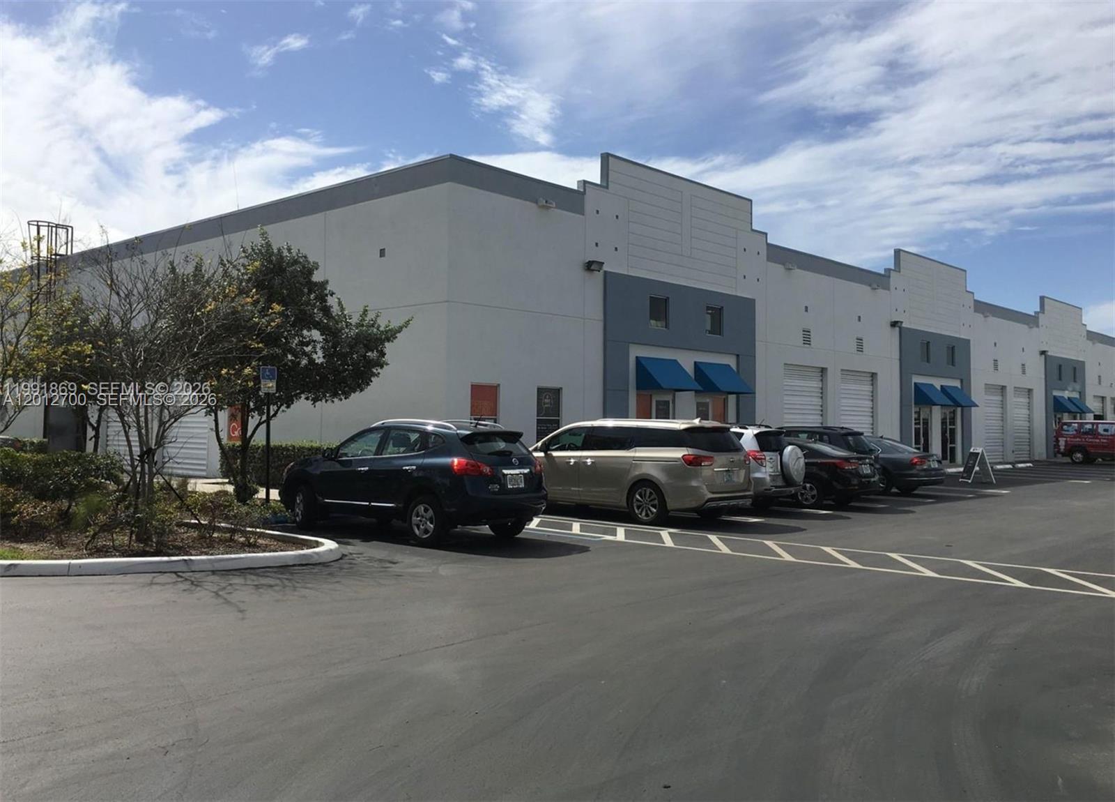 A row of commercial warehouse units with parking spaces in front under a blue sky — 2355 NW 70th Ave 11, Miami FL 33122, MIAMI, FL