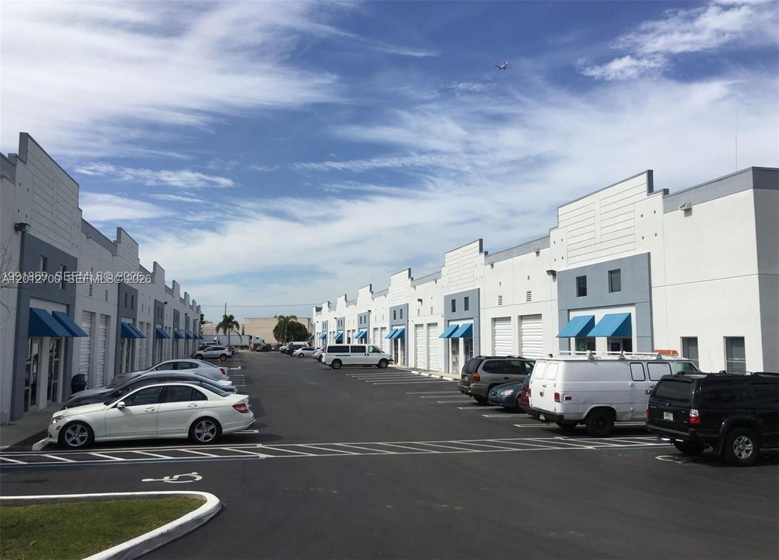 A parking lot sits between two rows of white industrial warehouse buildings with blue awnings — 2355 NW 70th Ave 11, Miami FL 33122, MIAMI, FL