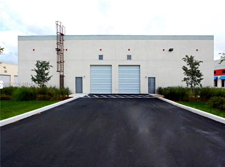 The exterior of a commercial warehouse building features two roll-up doors and a metal ladder — 2355 NW 70th Ave 11, Miami FL 33122, MIAMI, FL