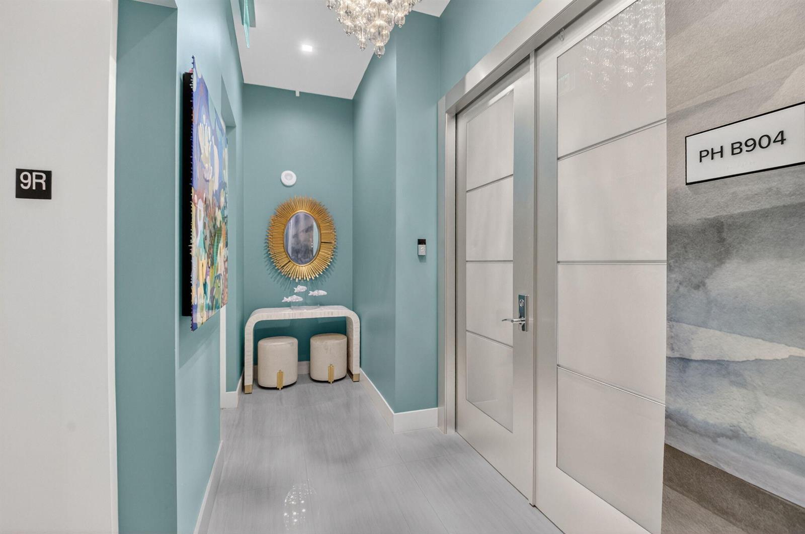 A teal-walled entryway features a sunburst mirror, a console table with stools, and double doors — 20155 Boca West Drive # b904, Boca Raton FL 33434, BOCA RATON, FL