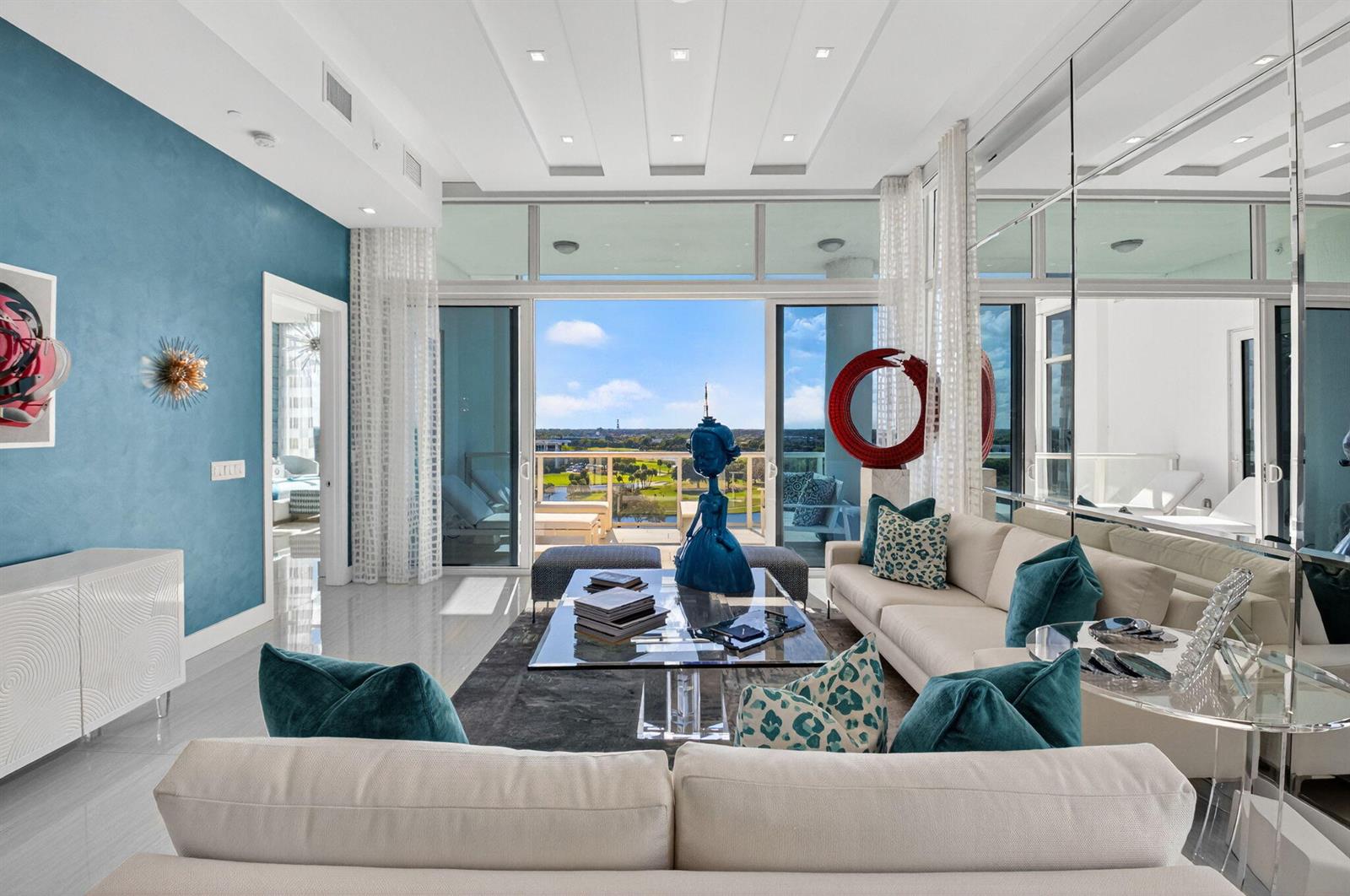 A modern living room with blue walls, white sofas, and a balcony overlooking a golf course — 20155 Boca West Drive # b904, Boca Raton FL 33434, BOCA RATON, FL
