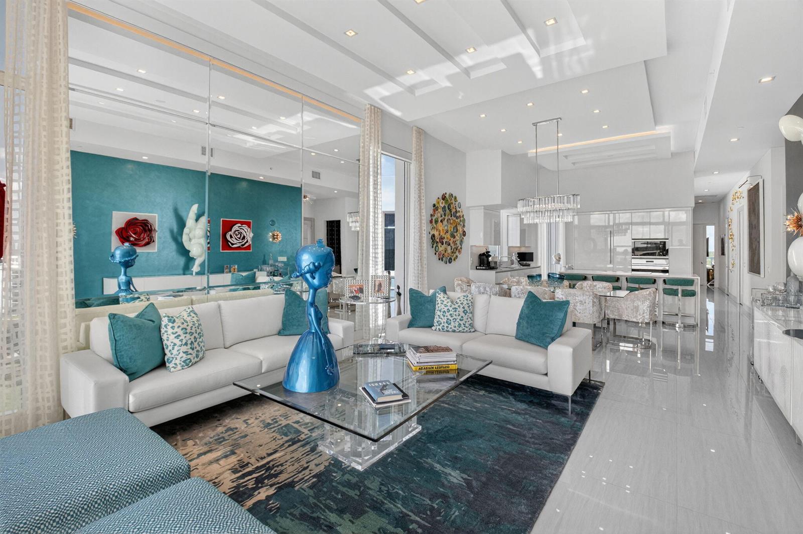 A modern living room features white sofas, a glass coffee table, and a teal accent wall — 20155 Boca West Drive # b904, Boca Raton FL 33434, BOCA RATON, FL