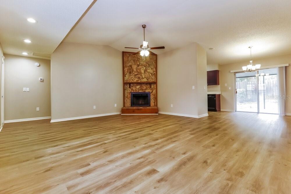 A living room with wood-look flooring, a stone fireplace, and an adjacent dining area — 1828 CRAVEN DRIVE, SEFFNER, FL