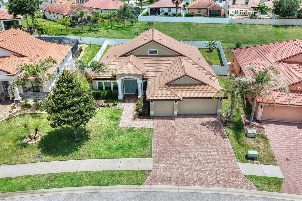 An aerial view of a single-story house with a tiled roof and brick paver driveway — 3935 SUNSET LAKE DRIVE, LAKELAND, FL