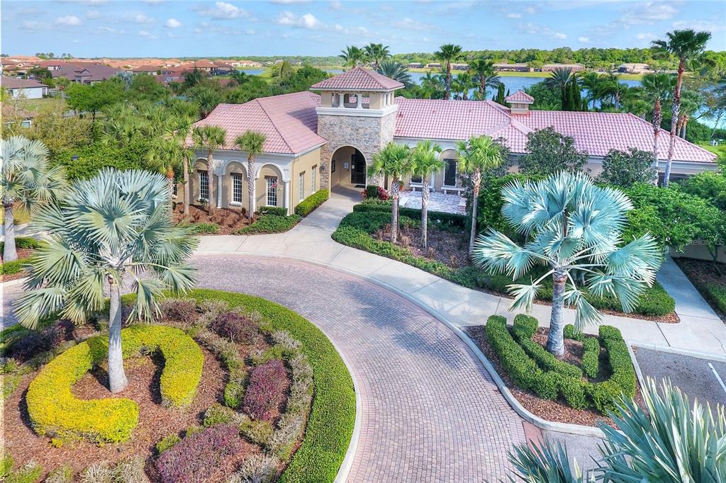 An aerial view shows a clubhouse with a tile roof, stone tower, and circular driveway — 3935 SUNSET LAKE DRIVE, LAKELAND, FL