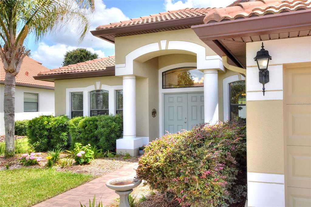 The exterior of a house features a light-colored front door, white columns, and landscaping — 3935 SUNSET LAKE DRIVE, LAKELAND, FL