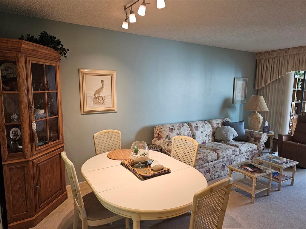 A dining area and living room feature a floral sofa, wooden hutch, and oval table — 586 LAKESIDE DRIVE UNIT 586, BRADENTON, FL