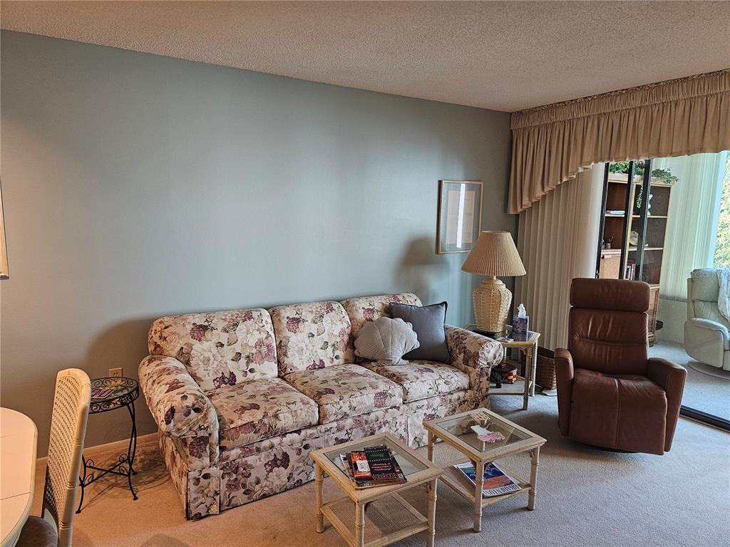 A living room features a floral sofa, a brown recliner, and two small glass-topped tables — 586 LAKESIDE DRIVE UNIT 586, BRADENTON, FL