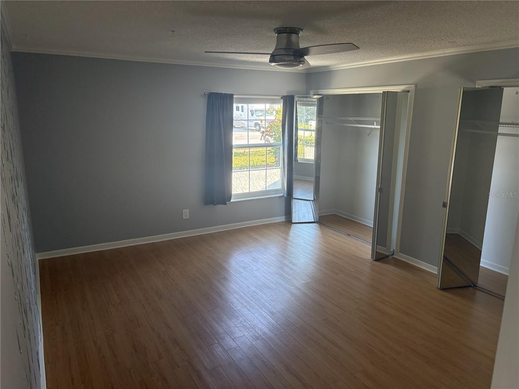 A bedroom with gray walls, wood-look flooring, a ceiling fan, and a mirrored closet — 5784 BAY PINES LAKES BOULEVARD, ST PETERSBURG, FL