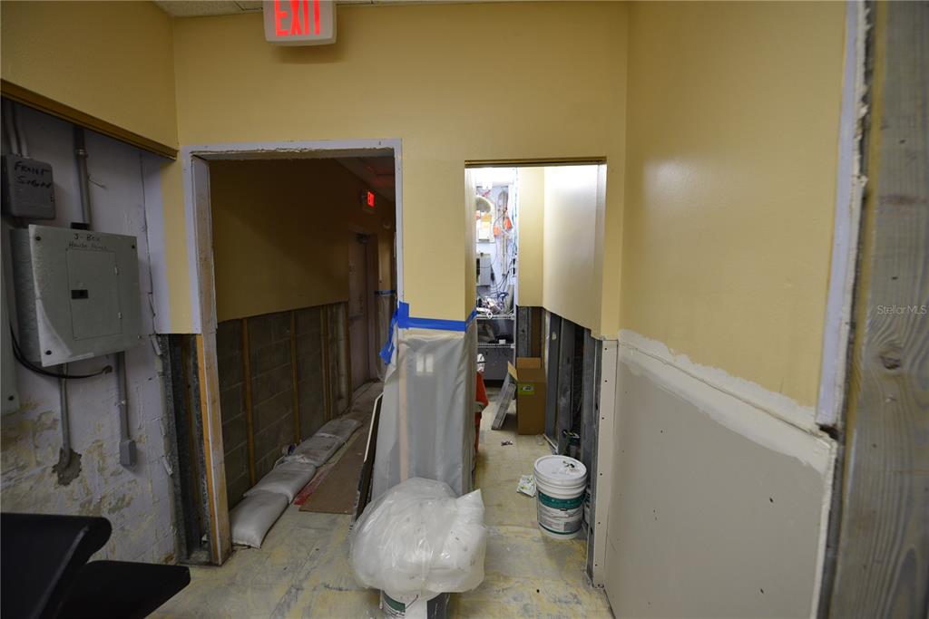 An unfinished interior hallway with exposed wall studs, drywall patches, and a bucket on floor — 5124 US HIGHWAY 19, NEW PORT RICHEY, FL